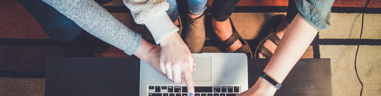 three person pointing the silver laptop computer